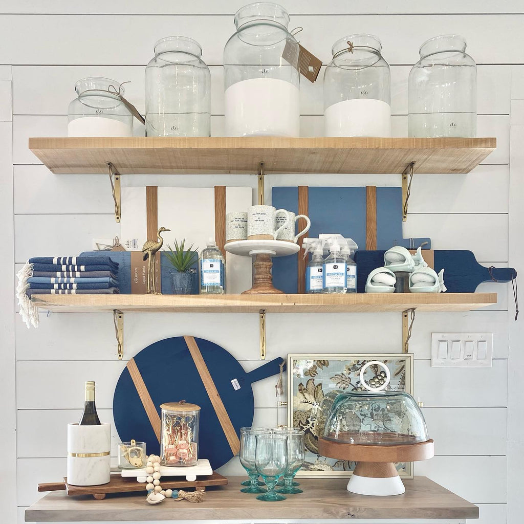 Coastal and elegant kitchen and tabletop accessories.  Accessories ranging from everyday to entertaining.  Arrangement of dish soaps, bar accessories, canisters, domes, cloches, cheese sets, trays and decanters.   