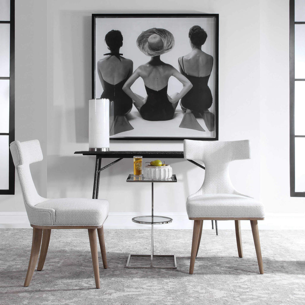 Two white chair around Martini Table with pictures hanging in the background