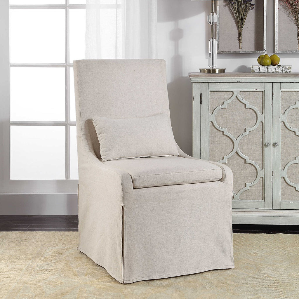 Room Setting / Accent Coley Armless Linen Covered Tailored Chair by Uttermost. This chair is perfect for dining or accent chair. Simplistic in form, this casually sophisticated armless chair features a tailored off-white linen blend slipcover with a plush cushion seat and kidney pillow for added comfort.