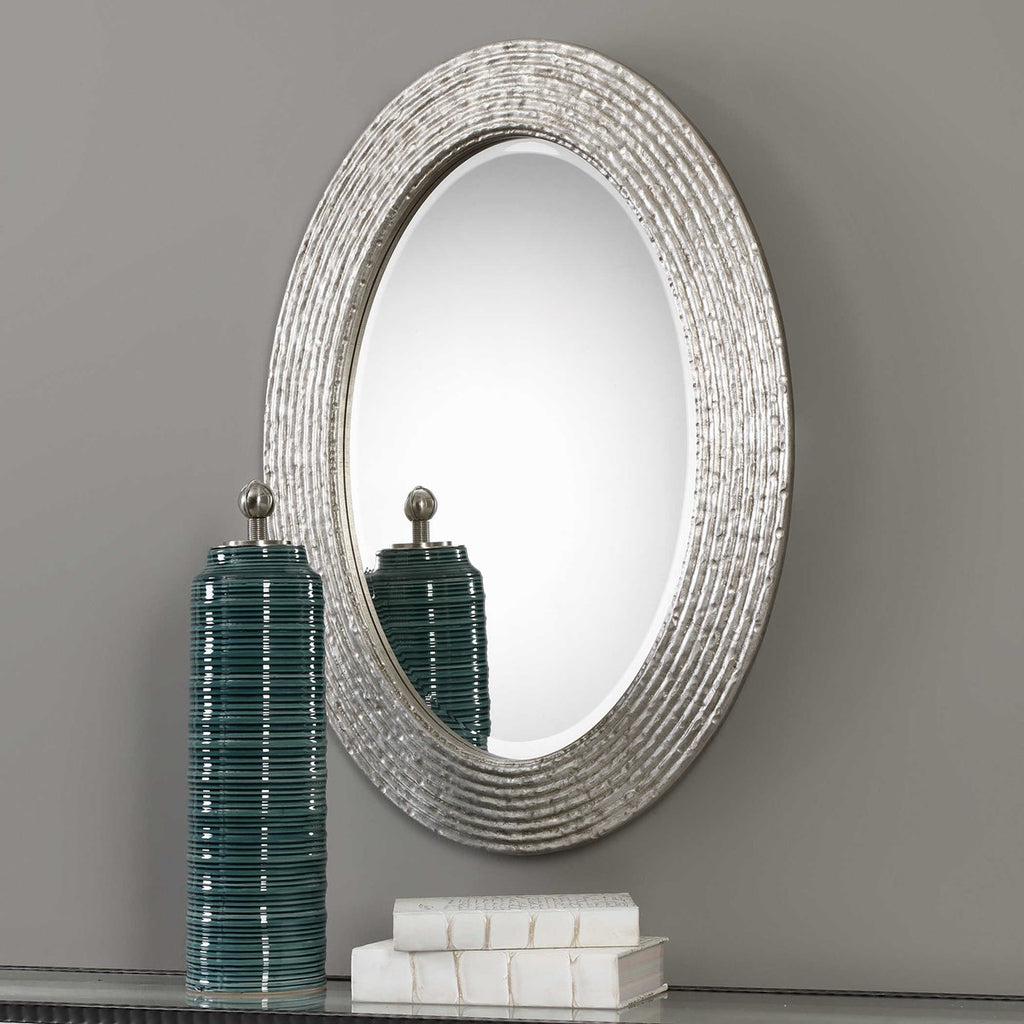 Room setting view. This oval frame features a reeded surface with a hammered texture and a burnished silver wrapped finish. Mirror is beveled and may be hung horizontal or vertical.