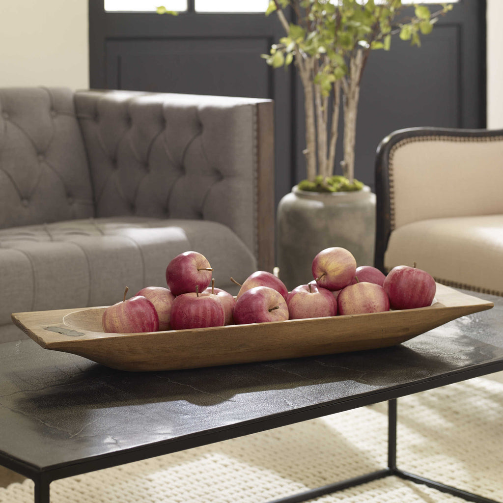 Solid reclaimed brown wood dough tray by Uttermost filled and displayed on coffee table.