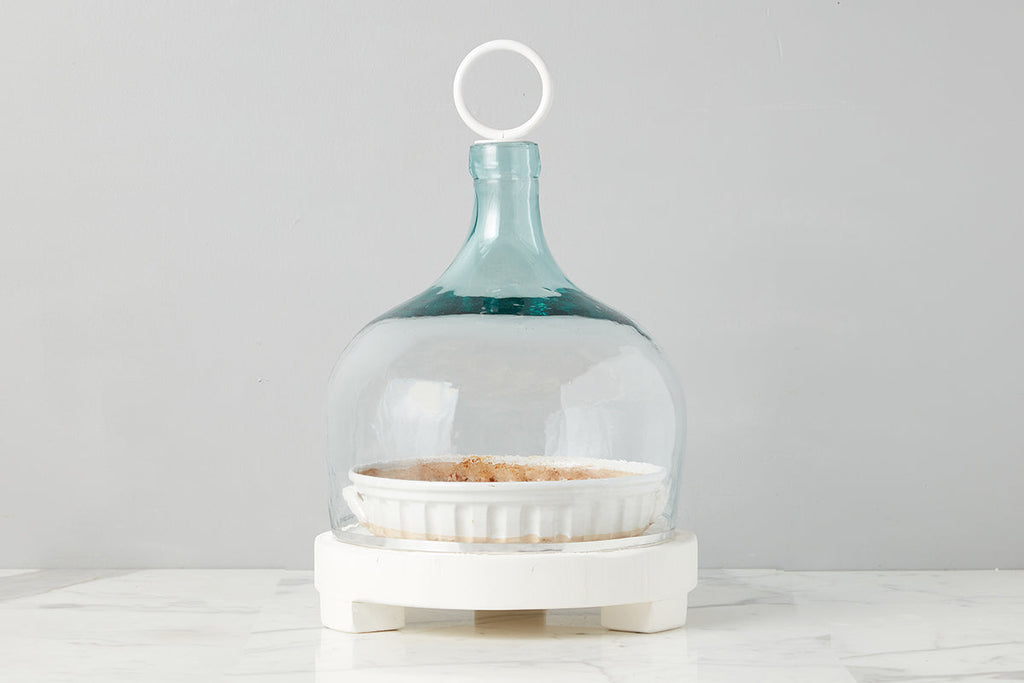 Bianca Glass Cloche by etúHOME. The silhouette of a classic wine bottle demijoh with iron handle. Sample of cloche on stand.